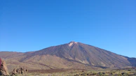The steaming crater of Oldonyo Lengai volcano under a clear blue sky.