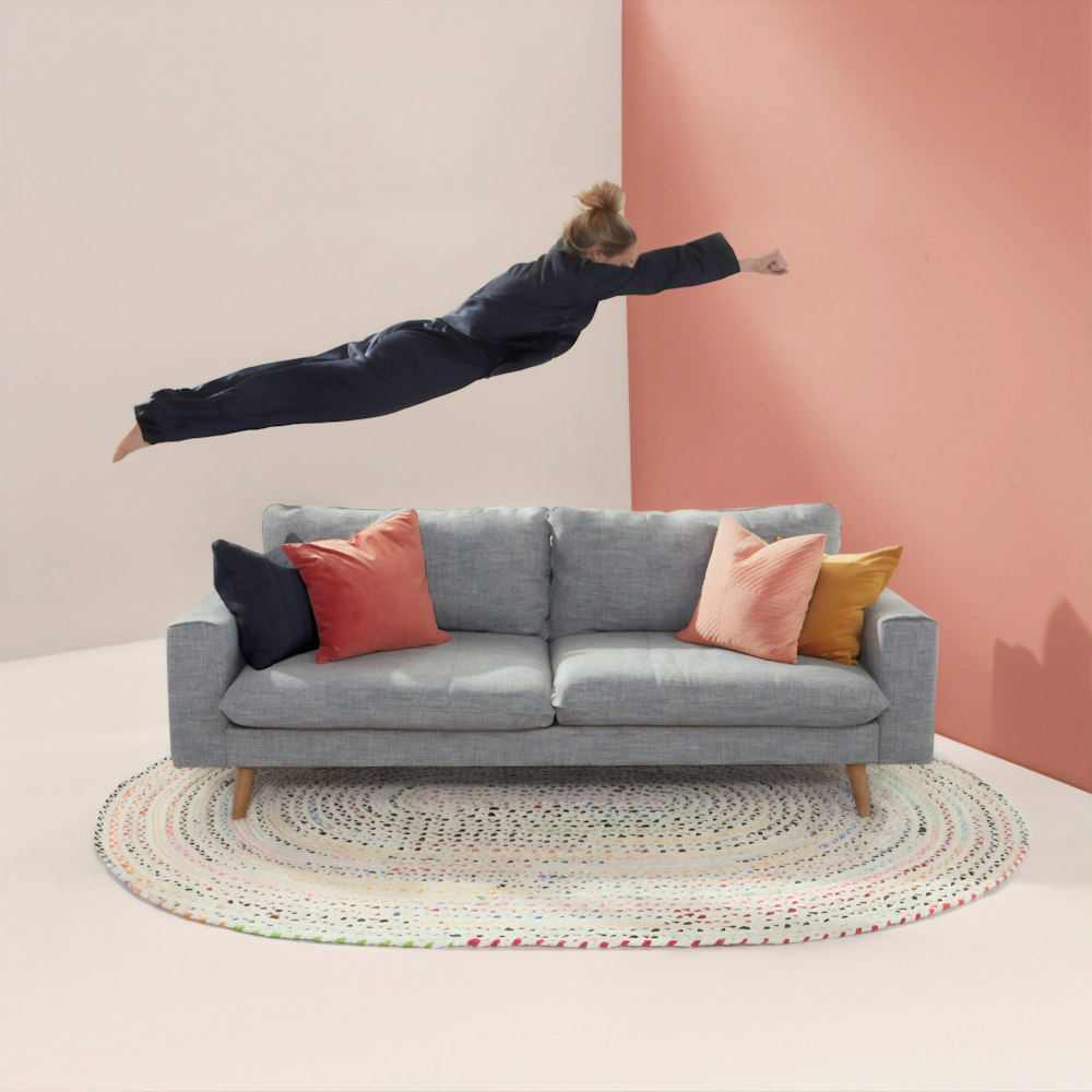 woman jumping in gray 2-seat sofa