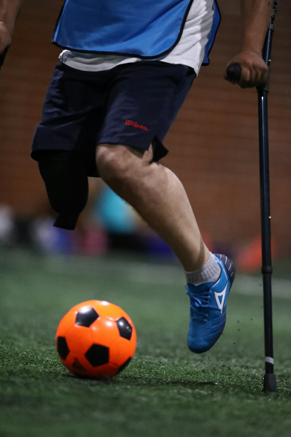 person using black cane playing soccer on field