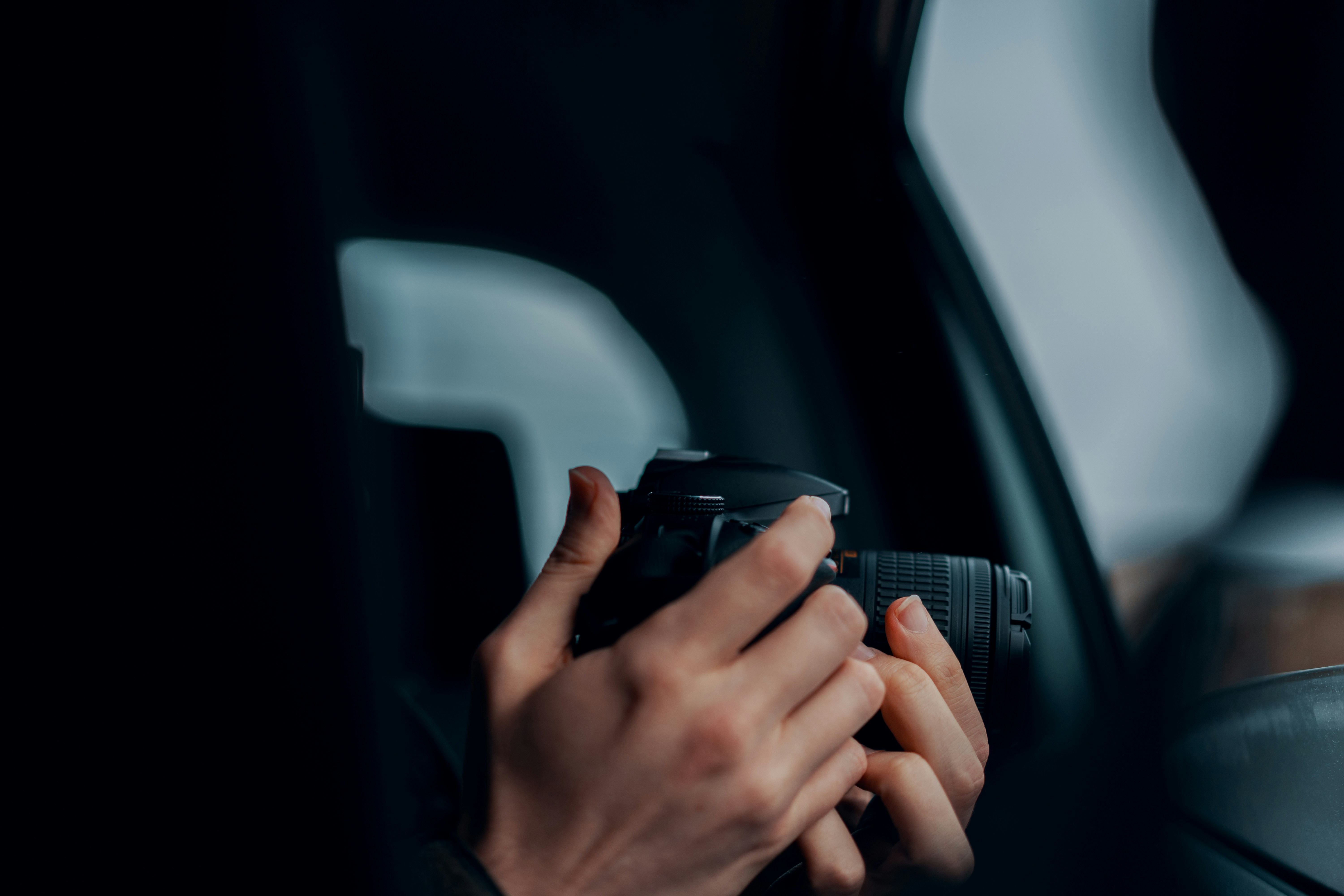 close up of hands holding iphone near luxury electric vehicle door handle