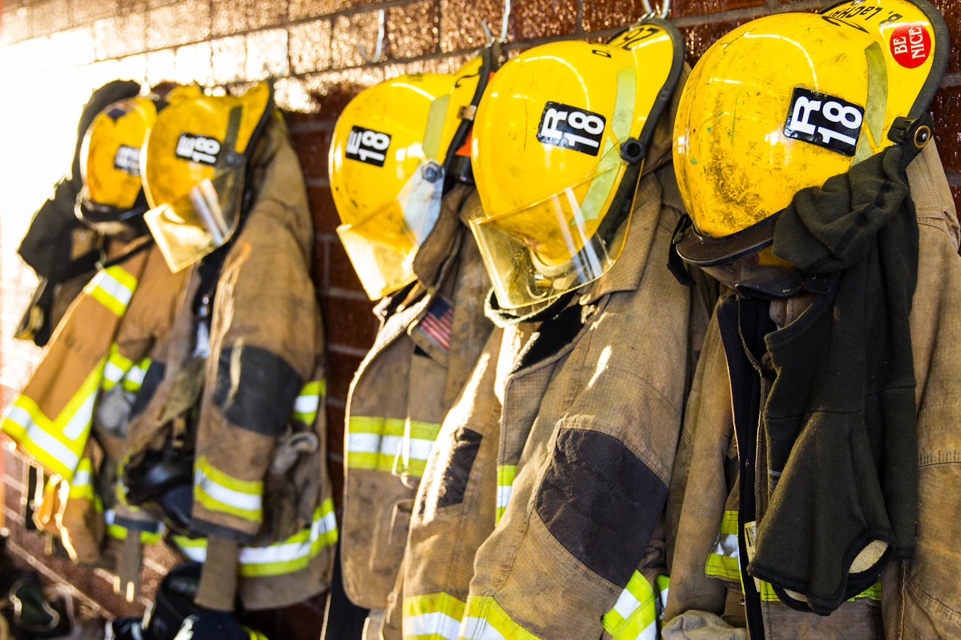 Firefighter turnout coats and helmets hanging in a station