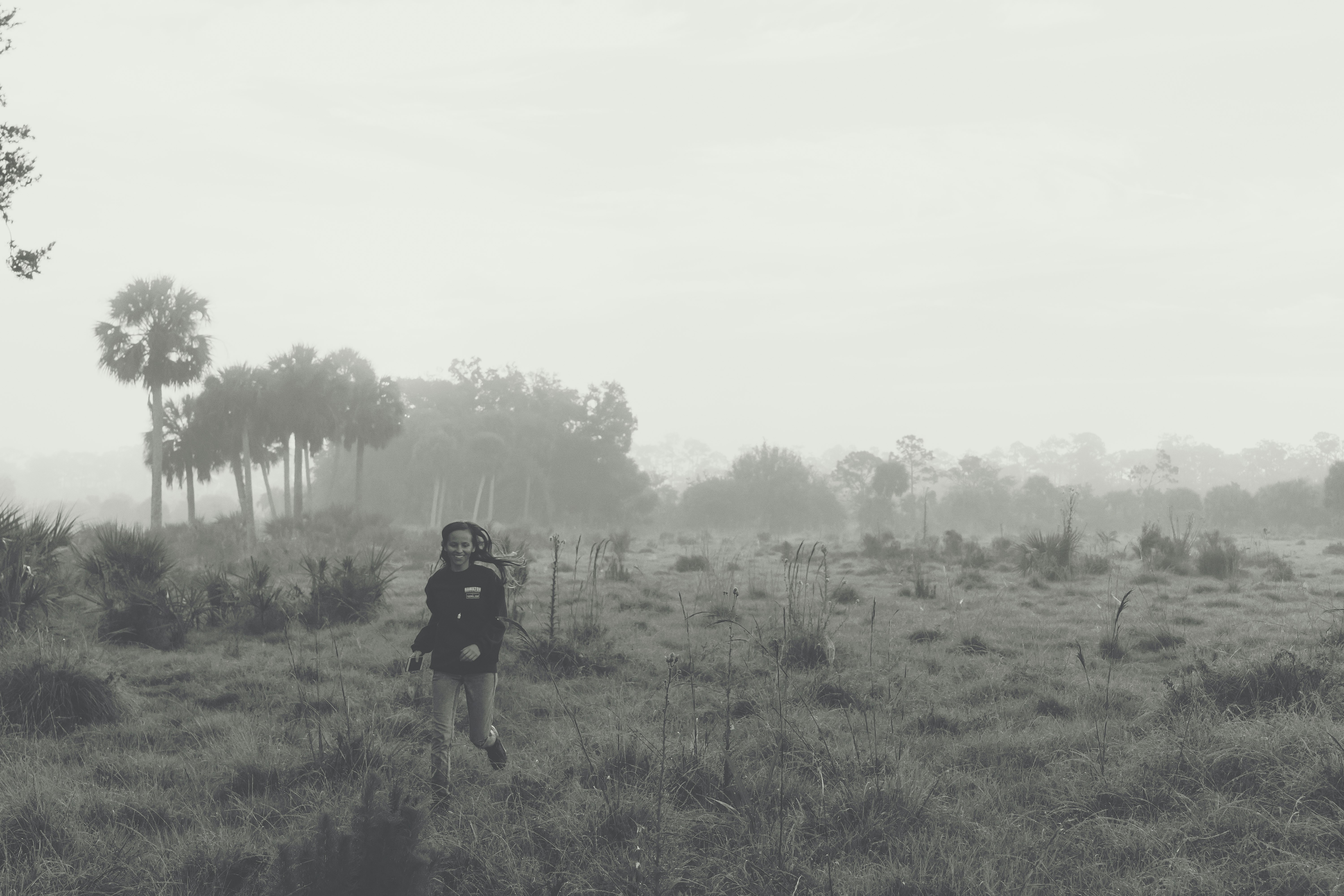 grayscale photo of person on grass field during daytime