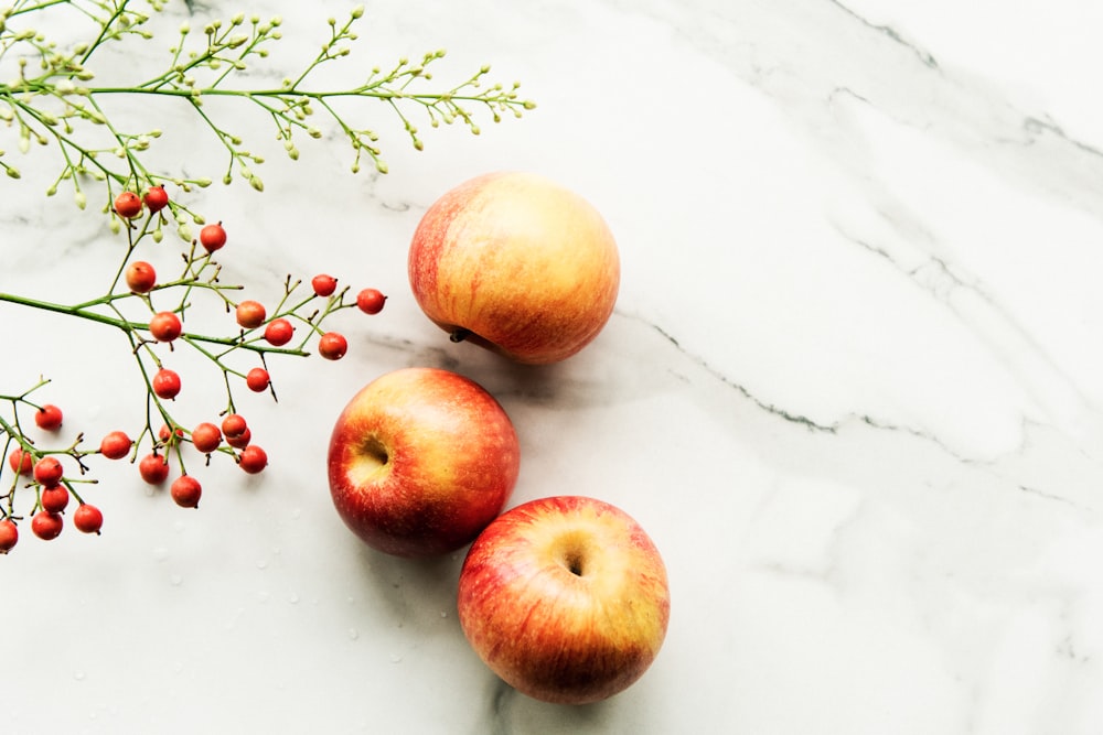 three apples on white surface