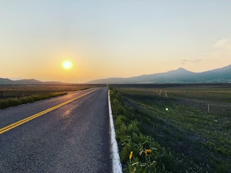 A freshly paved highway stretching through a mountainous landscape at sunset.