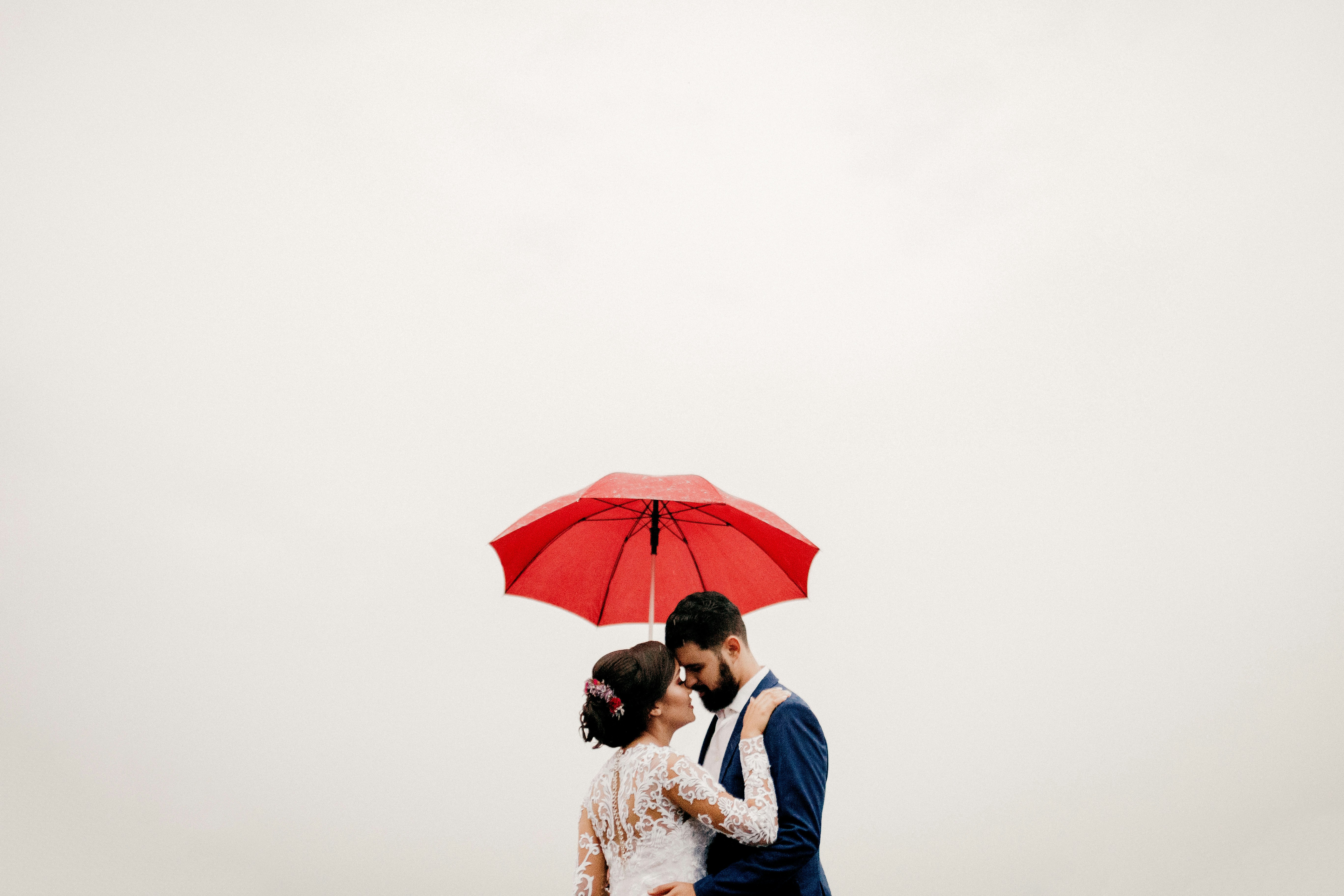 rainy wedding day wallpaper, romantic umbrella couple, cozy indoor wedding, dramatic storm sky, ilustrasi artikel Don't Let the Rain Dampen Your Spirits: Your Guide to Handling Bad Weather on Your Wedding Day 2