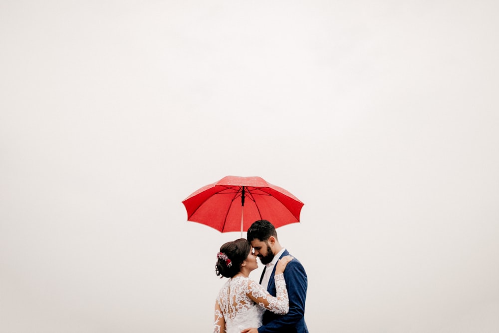 man and woman under red umbrella