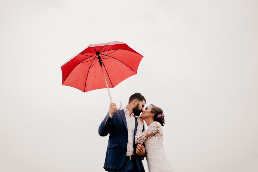 Mann und Frau unter rotem Regenschirm