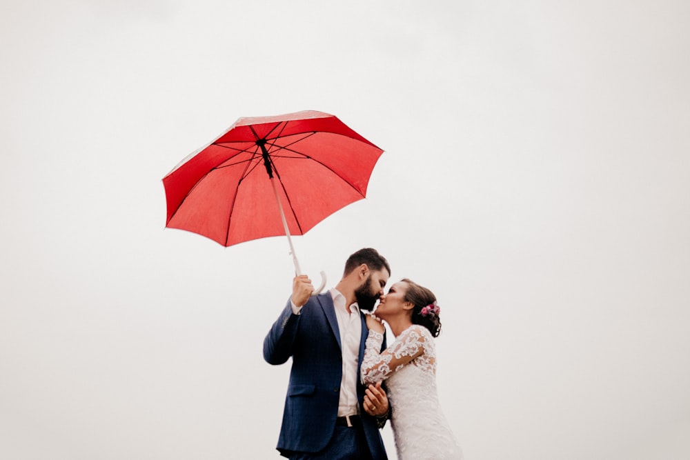 man and woman under red umbrella
