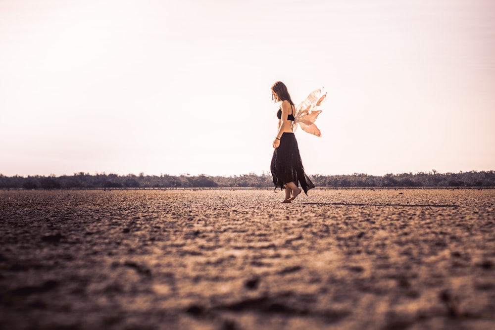 femme portant une robe noire marchant sur un champ ouvert