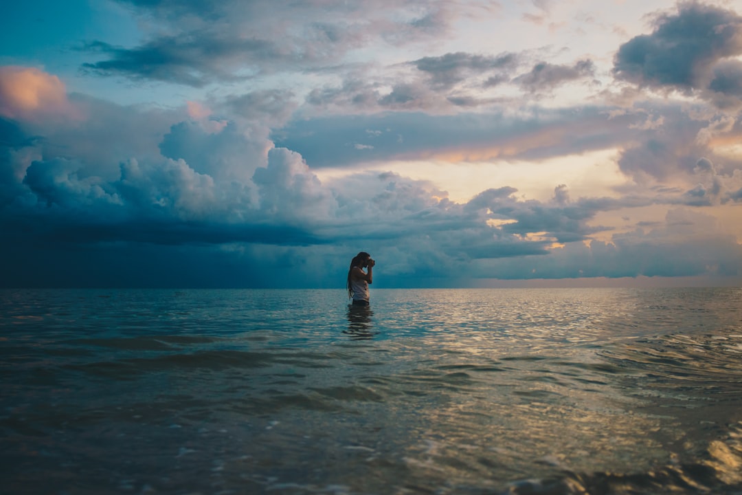 woman in sea under cloudy sky