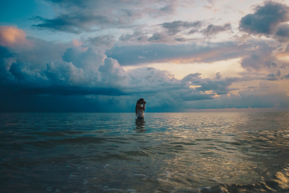 woman in sea under cloudy sky