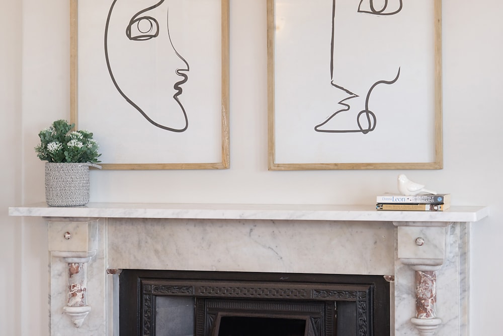 a fireplace in a living room with two paintings on the wall