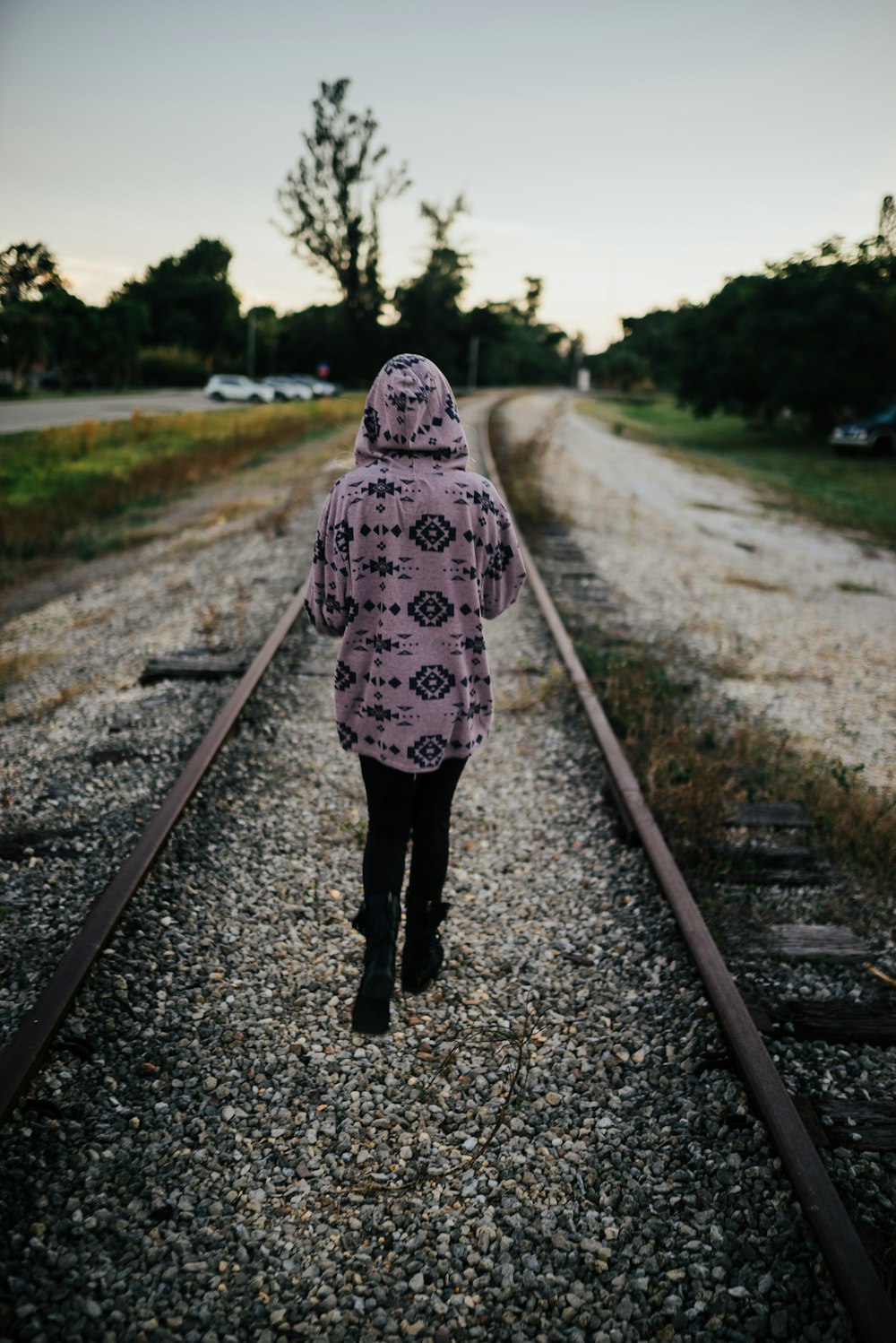 Person mit Kapuzenpullover, die tagsüber auf der Eisenbahn spazieren geht