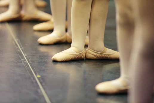 Photograph of a ballet master guiding young dancers during a rehearsal in a bright studio