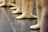 Several ballet dancers stand in a line, focusing on their feet clad in soft ballet slippers. The dancers are aligned on a smooth studio floor, possibly in preparation for a class or rehearsal.