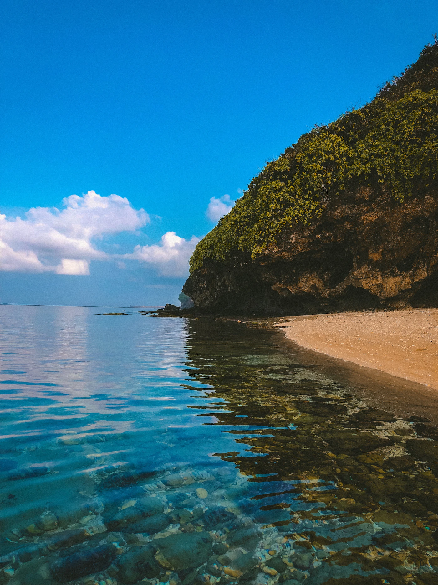 A green coastal headland beside blue water in Bali.