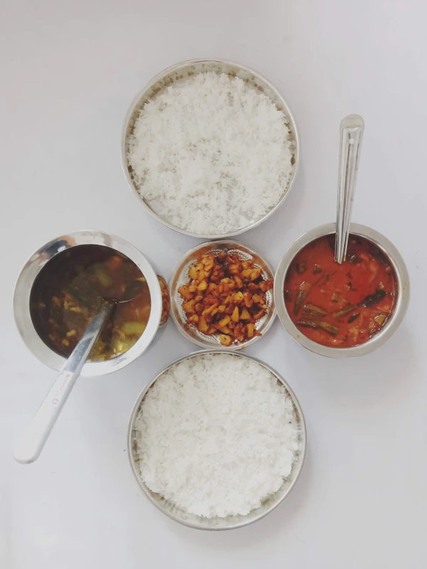 Bowls of sambar and clear peppery rasam served alongside steamed rice