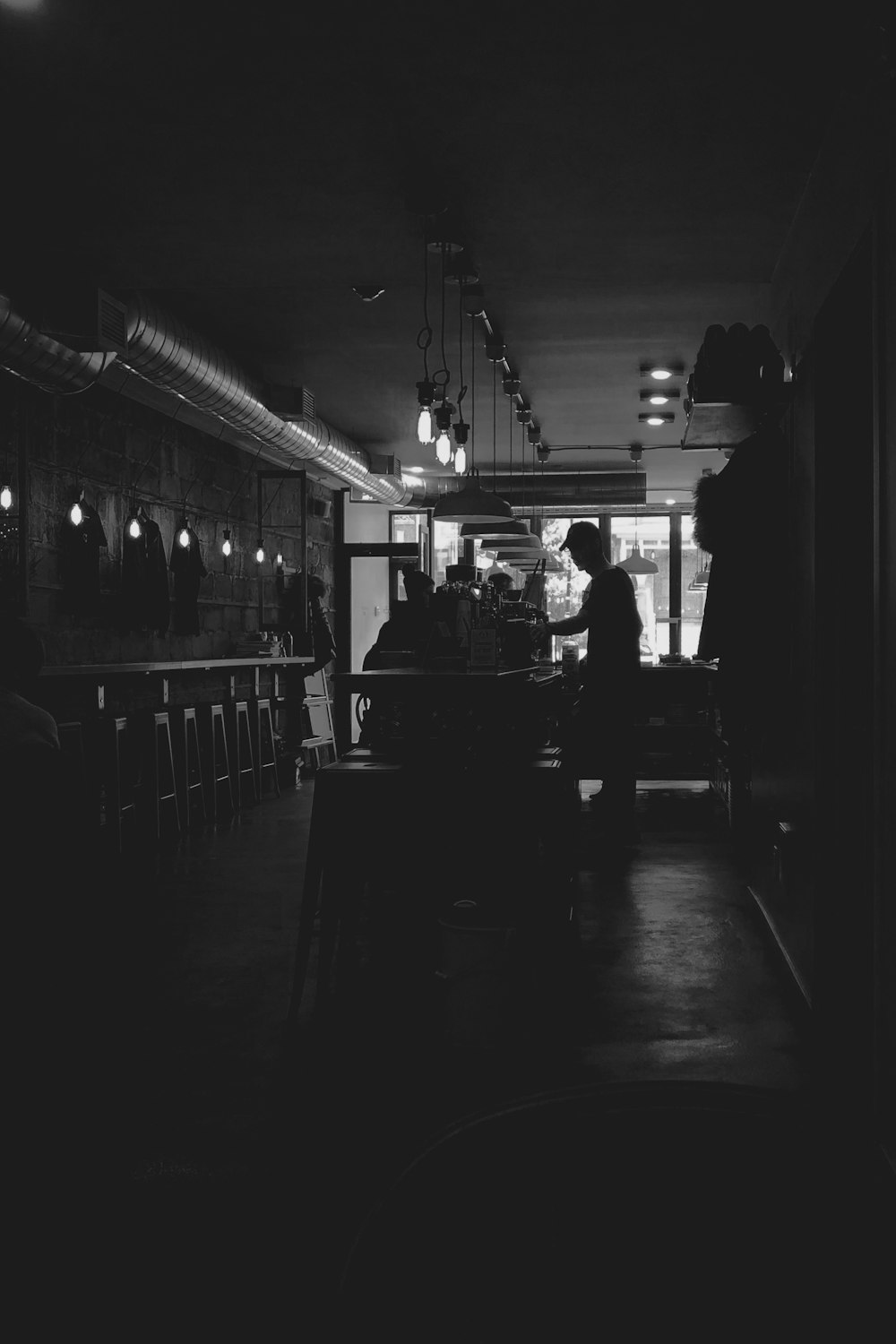 a black and white photo of people sitting at a bar