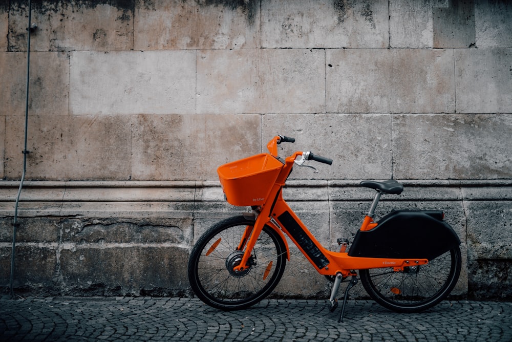 orange bike parked beside wall