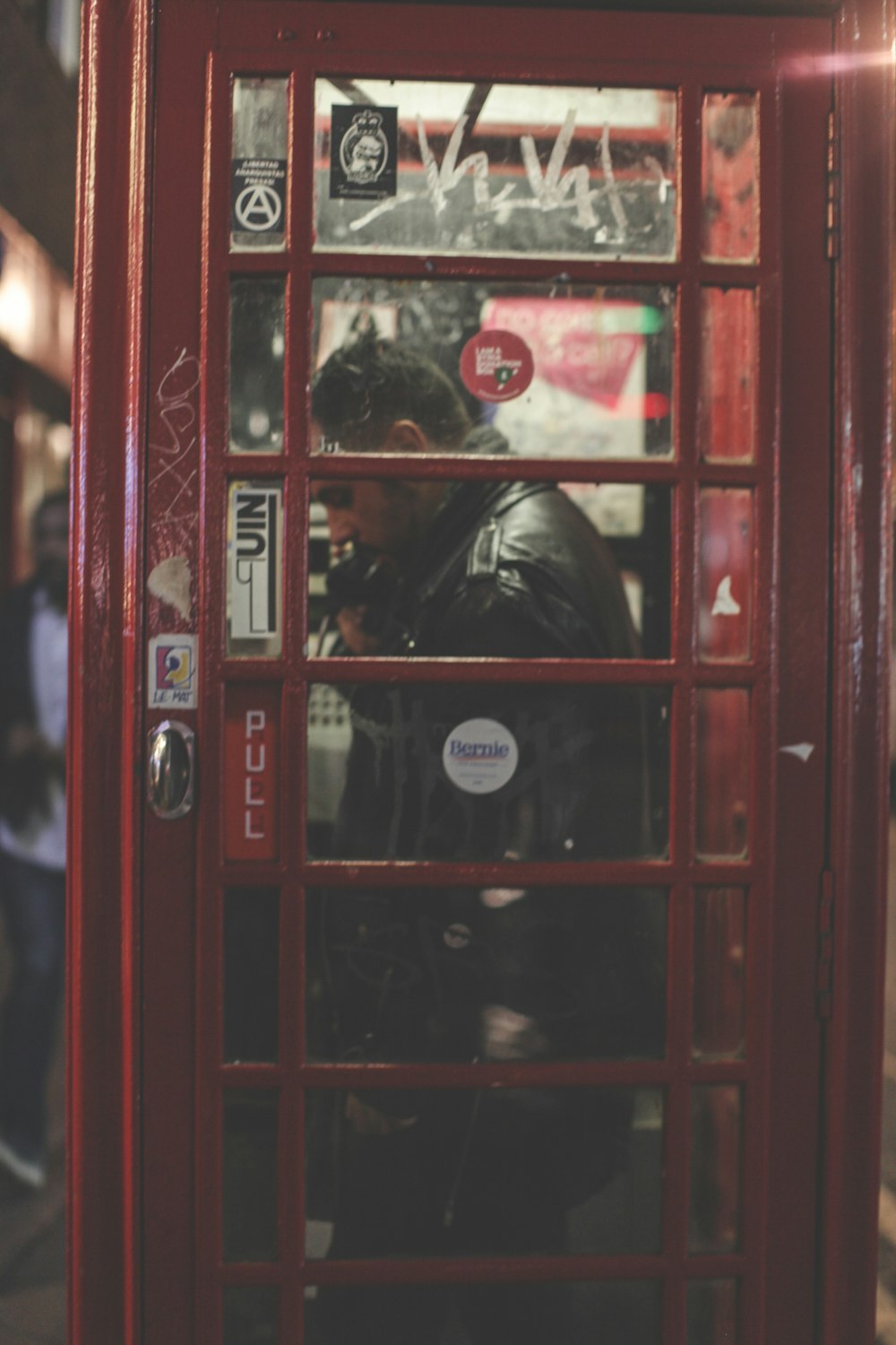 man inside telephone booth wearing black leather jacket