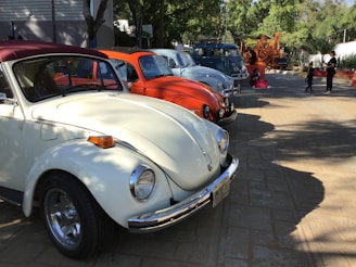A lineup of colorful vintage VAG cars parked side by side under a clear blue sky at a retro meet.