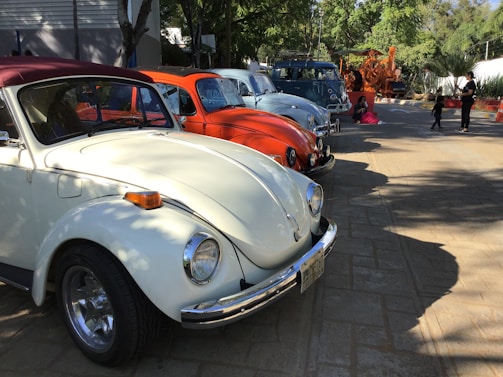 A lineup of colorful vintage VAG cars parked side by side under a clear blue sky at a retro meet.
