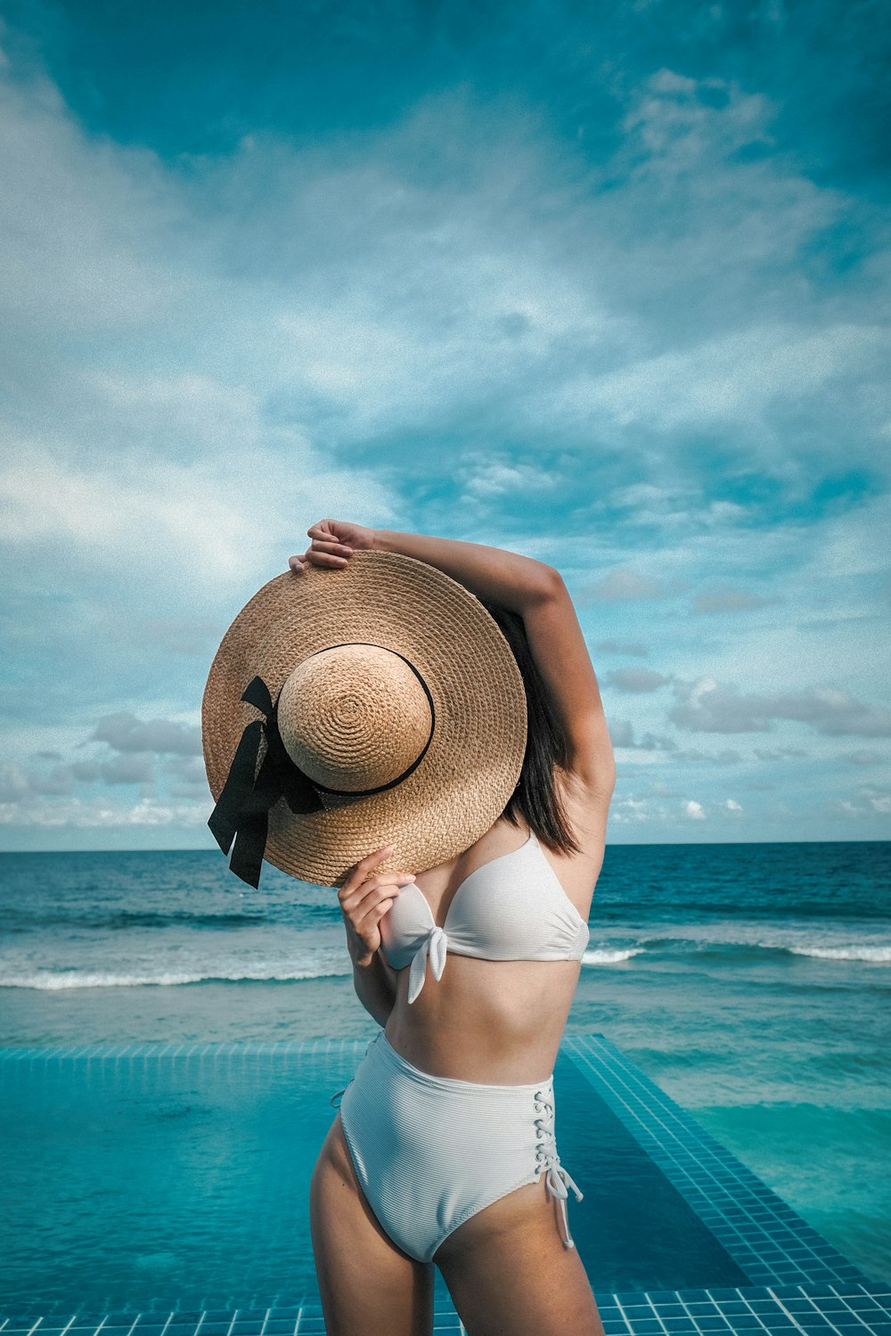 Mujer sosteniendo sombrero de paja marrón