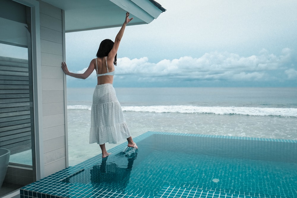 woman in white dress standing beside pool