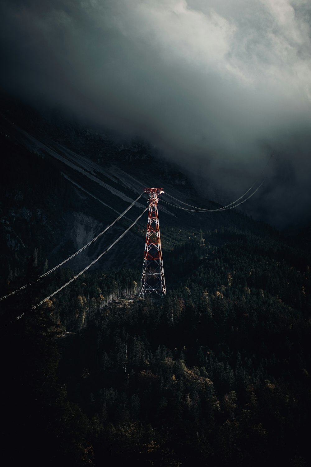 red and white electric tower on hill