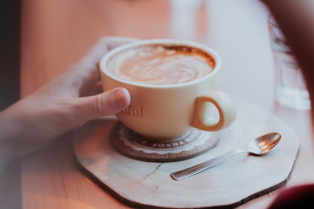 shallow focus photo of white ceramic mug beside stainless steel spoon