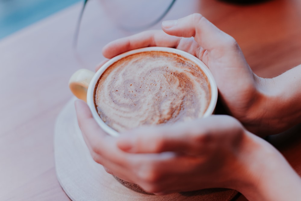 person holding white cappuccino cup