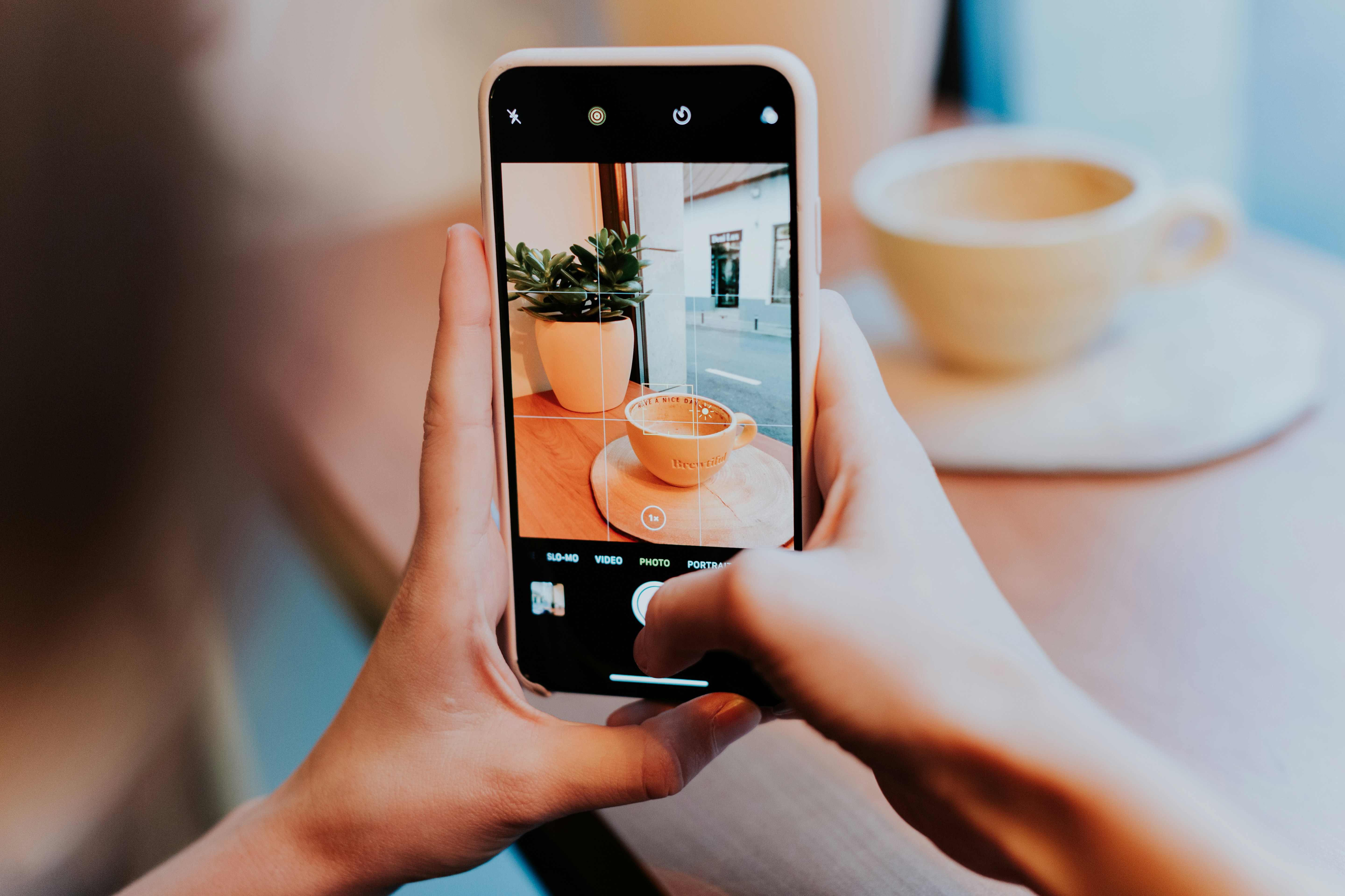 person taking photo of white ceramic teacup