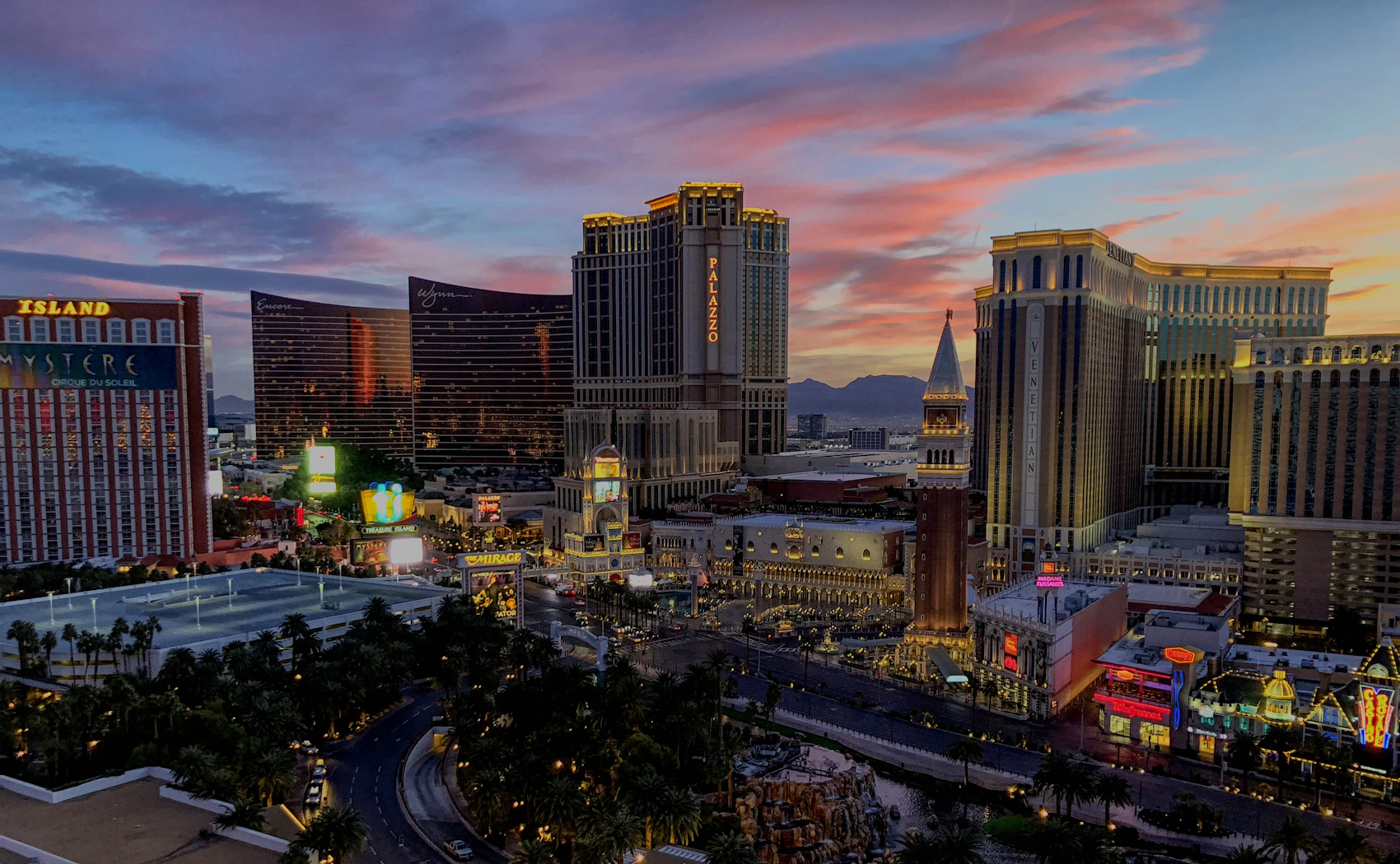A wide elevated view of Las Vegas resorts at dusk with desert mountains beyond