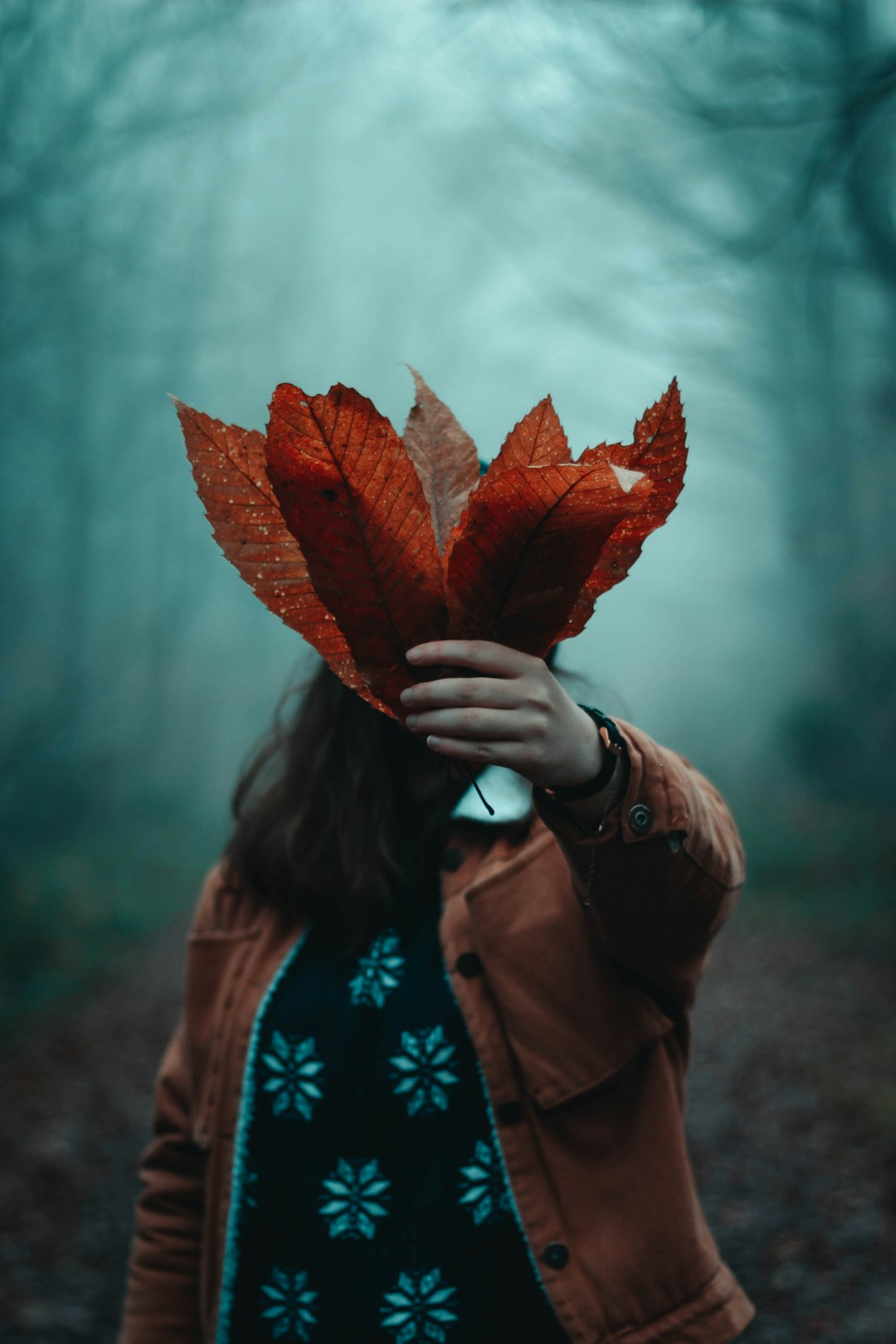 selective focus photography of girl holding leaves