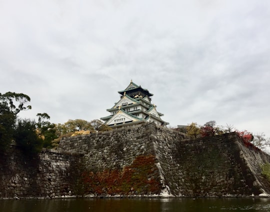 temple in front of calm body of water in Osaka Castle Park Japan