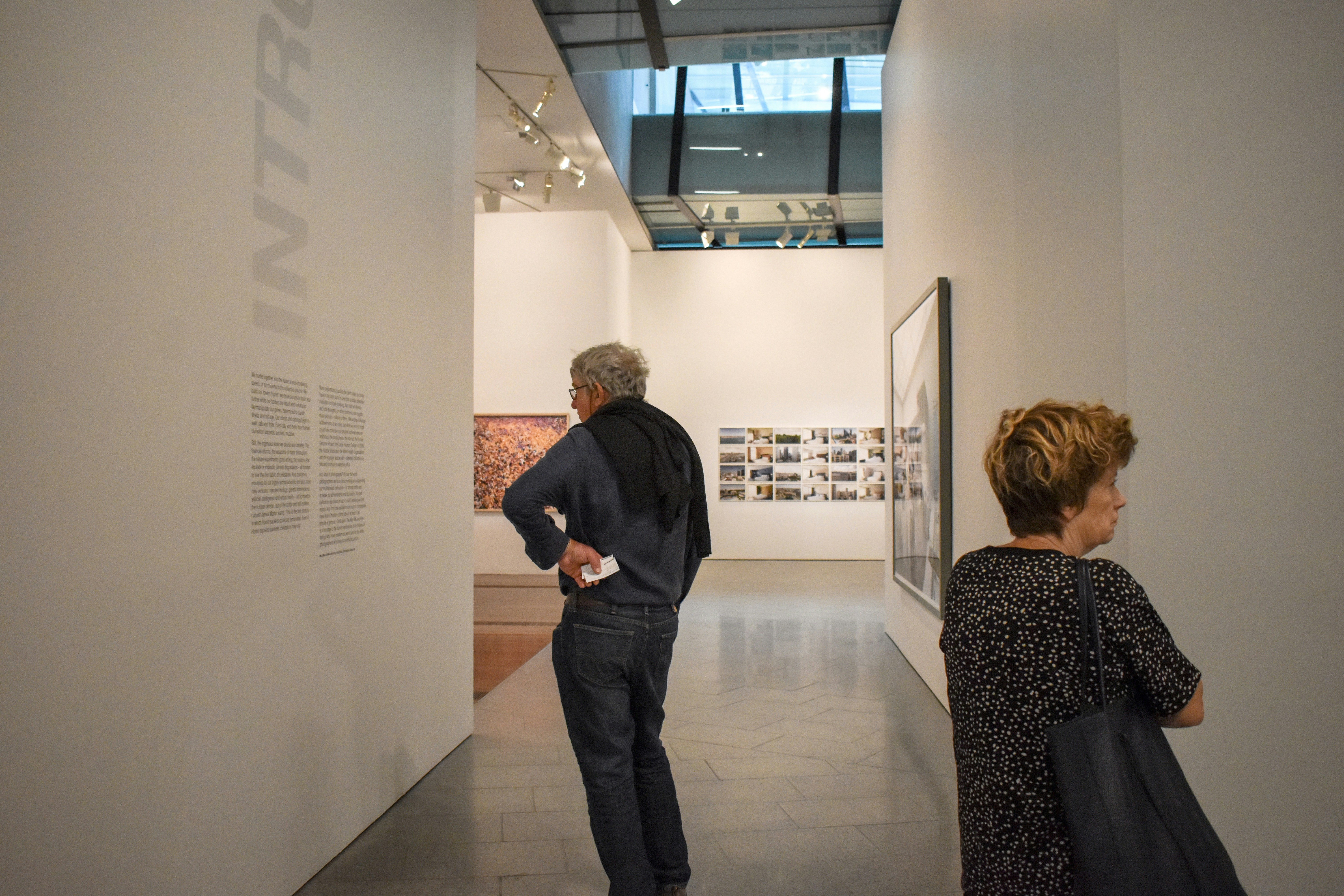 Bright museum gallery with soft spotlights on impressionist paintings, clean white walls, open airy space
