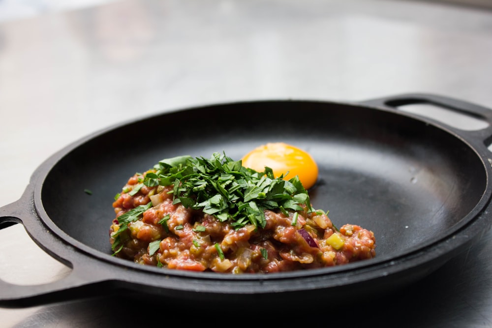 ground meat with chopped parsley and egg on round black tray