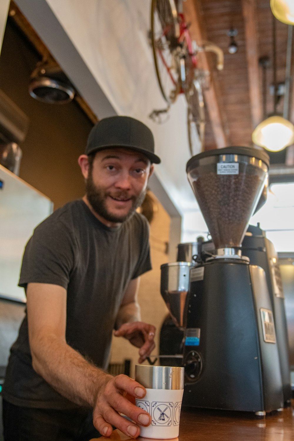 man standing in front of black and gray coffeemaker holding white and silver coffee cup