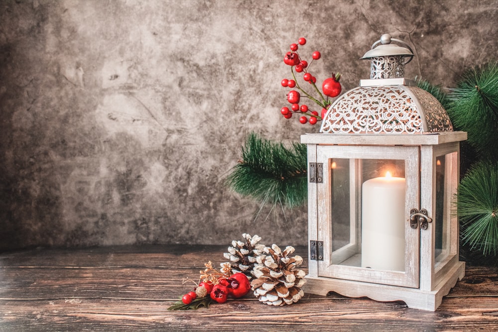 white pillar candle in lantern beside wall