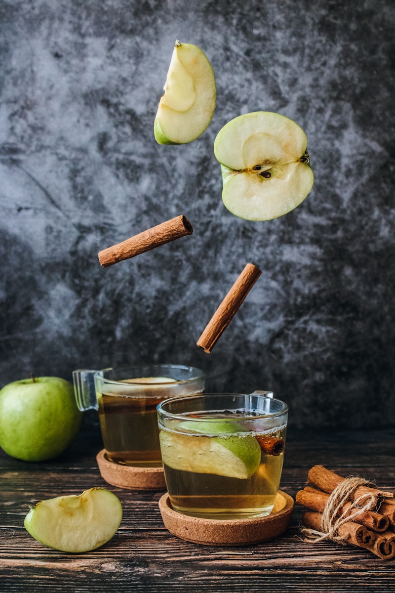 Cups of spiced apple cider with sliced apples and cinnamon sticks