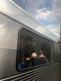 Passengers on a train looking out the windows, smiling and reflecting.