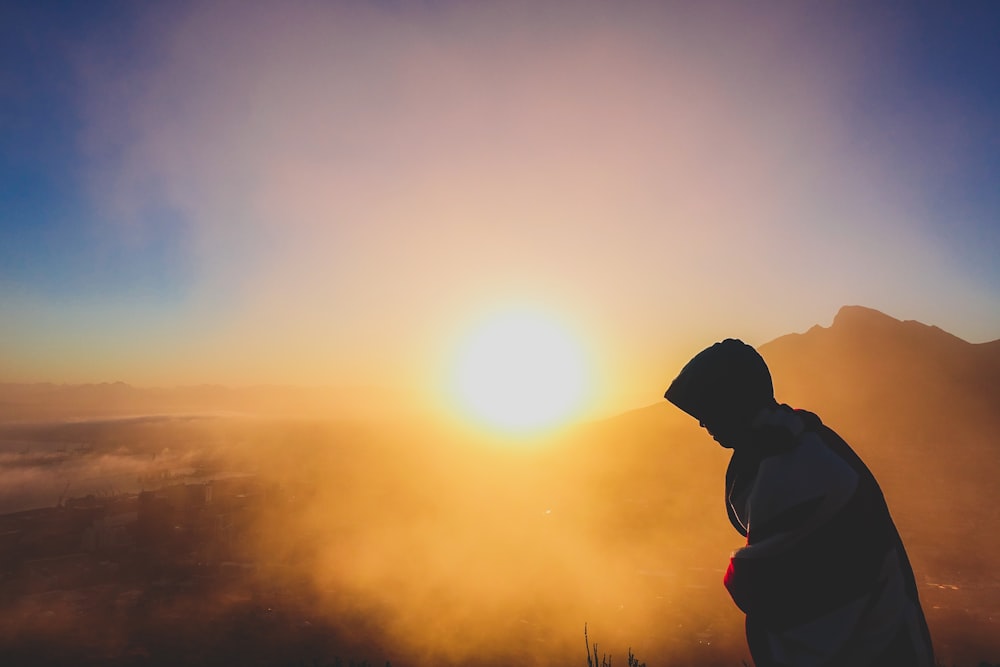 eine Person, die bei Sonnenuntergang auf einem Berg steht