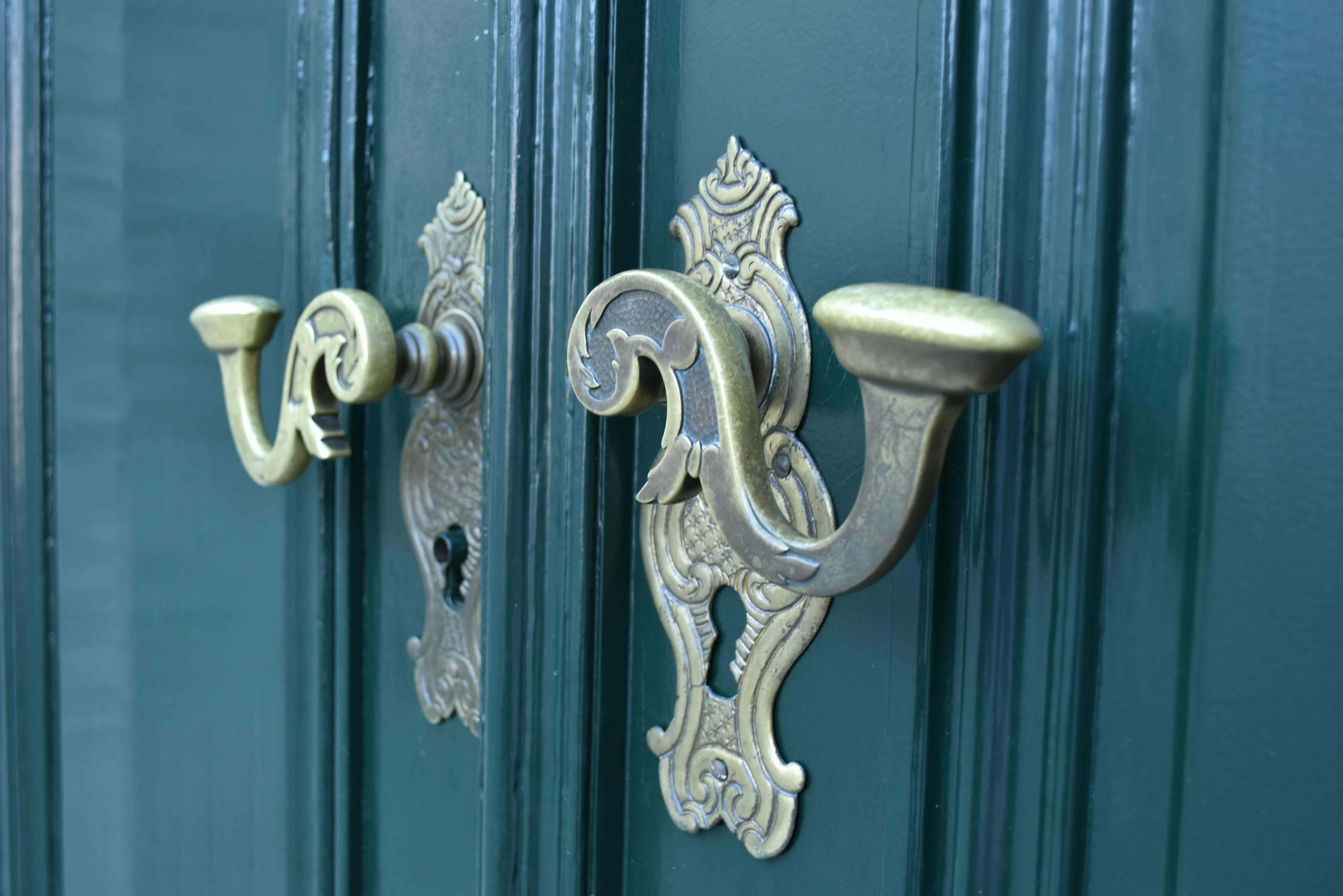 Hotel entrance at night, brass door handles, dark green facade, soft lantern light