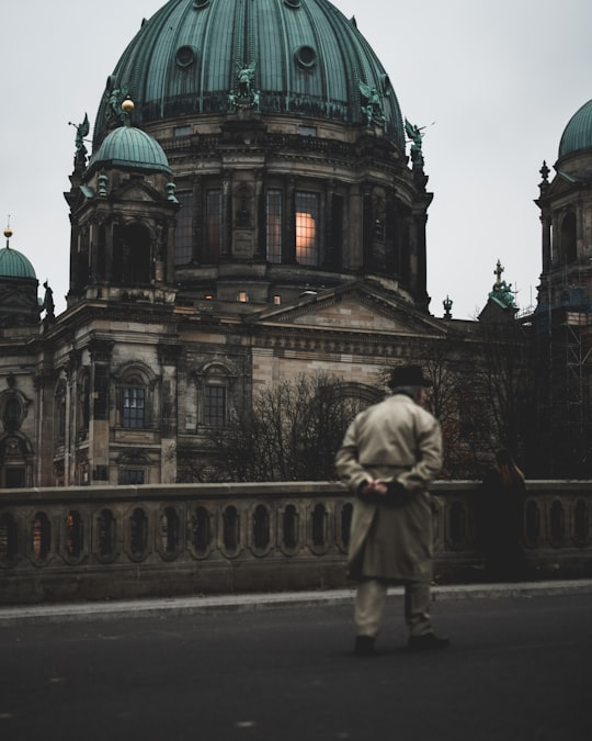man walking on bridge near brown concrete dome building in Berlin Cathedral Germany