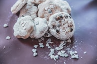 Freshly baked cookies with heart shapes and pastel icing, laid out on parchment paper.