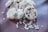 A pile of heart-shaped cookies dusted with powdered sugar, adorned with small heart decorations. Some cookies have chocolate chips embedded in them, and there are loose sugar hearts scattered around.