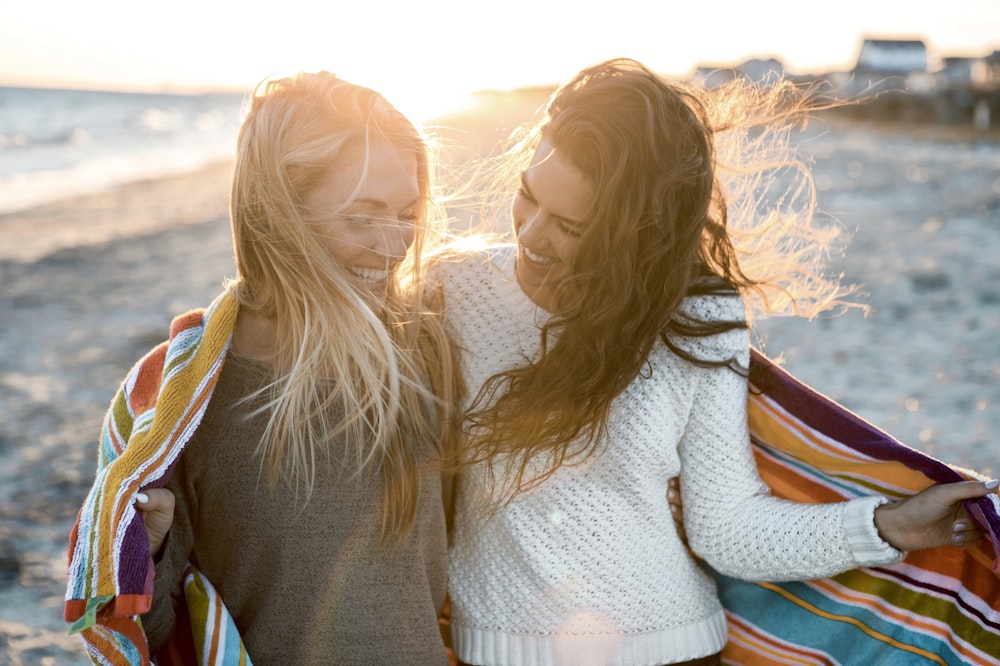 woman wearing gray and white sweater walking on seashore