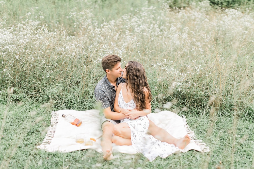 man and woman sitting on picnic mat