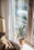 A sunlit living room corner with soft cushions, a warm throw, and a small potted plant on a wooden side table.