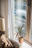 A sunlit living room corner with soft cushions, a warm throw, and a small potted plant on a wooden side table.